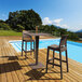 A Siesta Jamaica brown wickerlook resin outdoor barstool on a wooden deck next to a pool.