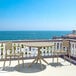 A Siesta Sky round taupe table and chairs on a balcony overlooking the ocean.