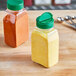 A couple of rectangular plastic spice containers on a table with yellow and red spices inside.