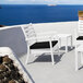 A Siesta Artemis XL white outdoor club arm chair with a black cushion on a white surface overlooking the ocean.