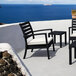 An outdoor patio with Siesta Artemis XL Black outdoor club arm chairs and a table with Sunbrella Natural cushions.