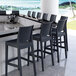 A Siesta Jamaica dark gray wickerlook outdoor barstool on a counter in a cocktail bar.