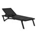 A Siesta Pacific black resin outdoor chaise lounge with black sling on a outdoor patio table.