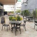 A black Siesta Helen outdoor dining chair on a tile patio with a table.