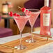 A wooden tray with two glasses of Fluere Non-Alcoholic Raspberry Blend Pink Gin with raspberries.