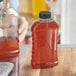 A person pouring honey into a ribbed hourglass PET honey bottle on a table.