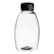 A clear plastic Classic Queenline honey bottle with a black flip top lid.