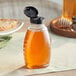 A Classic Queenline PET honey bottle filled with honey on a table.