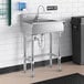A stainless steel Regency hand sink with a Waterloo hands-free faucet above it.