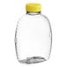 A clear plastic Queenline honey bottle with a yellow flip top lid.