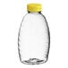 A clear plastic Classic Queenline honey bottle with a yellow flip top lid.