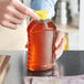 A person pouring honey into a Ribbed Hourglass PET Honey Bottle on a kitchen counter.