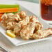 A plate of chicken wings with lemon pepper sauce and carrots.