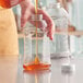 A person pouring honey into a ribbed plastic bottle.