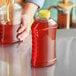 A hand pouring honey into a Ribbed Hourglass PET Honey Bottle.