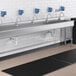 A Waterloo wall mount hand sink with 5 hands-free faucets over a black counter.