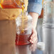 A person pouring honey into a Ribbed Hourglass PET Honey Bottle.