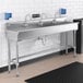 A stainless steel Regency hand sink with three Waterloo wall mount hands-free sensor faucets.