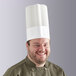 A man wearing a Choice disposable white chef hat smiling.