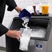 A person pouring ice into a Manitowoc undercounter ice machine bin.