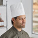 A man wearing a white Choice pleated disposable chef hat.