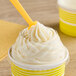 A close up of a yellow Choice clear plastic lid with a spoon in a frozen yogurt cup.