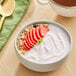 A bowl of Chobani strawberry Greek yogurt with strawberry slices and oat flakes.