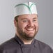 A smiling man wearing a green striped Choice disposable chef hat.