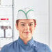 A woman wearing a green striped Choice disposable chef hat.