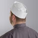 A man wearing a white Choice adjustable disposable chef hat.