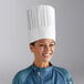 A woman wearing a white Choice pleated disposable chef hat.