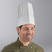 A man wearing a white Choice pleated disposable chef hat.
