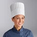 A woman wearing a white Choice fully formed pleated chef hat.