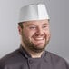 A smiling chef wearing a white Choice adjustable disposable overseas cap.