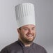 A man wearing a Choice white pleated disposable chef hat.