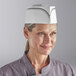 A woman wearing a Choice black stripe disposable chef hat.