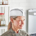 A woman wearing a Choice black striped disposable chef hat.