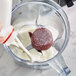 A blender with red and white Blender Bites Power Berry smoothie pucks in it.