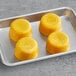 A metal tray of yellow Blender Bites Daily Defen-C smoothie pucks on a gray surface.