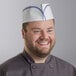 A smiling chef wearing a blue striped Choice disposable chef hat.