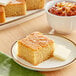 A plate of Abe's vegan cornbread with butter on a table with a bowl of chili.