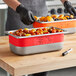 A man using Vigor Write-On Food Pan Bands to label two stainless steel food pans on a table.