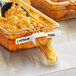 A plastic Vigor high-heat food pan label in a container of macaroni and cheese with a spoon.