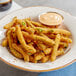 A plate of Birds Eye Crispy Green Beans with a cup of sauce.