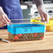 A person wearing gloves writing on a stainless steel food pan lid.