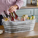 A man holding a Behrens steel oval tub with a bottle of beer in ice.