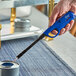 A hand using a blue Choice wind-resistant lighter to light a can of food.