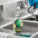 A gloved hand uses Seventh Generation Yuzu Basil dishwashing liquid to clean a sink.