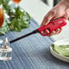 A hand using a red Choice Multi-Purpose Lighter to light a candle on a table with a green napkin.