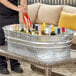 A man pouring wine into a Behrens steel tub on a patio table.